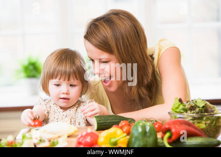 Mère et fille en cuisine faire une salade smiling Banque D'Images