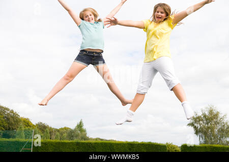 Deux jeunes filles sautant sur trampoline smiling Banque D'Images