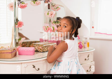 Jeune fille assise à miroir dans chambre smiling Banque D'Images