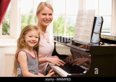 Woman and young girl playing piano and smiling Banque D'Images