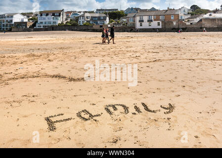 Le mot famille écrit dans le sable sur la plage de Porth Newquay en Cornouailles. Banque D'Images