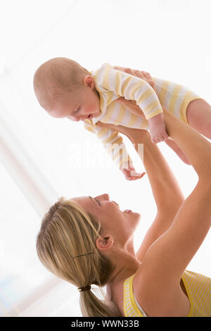 Mother holding baby indoors smiling Banque D'Images