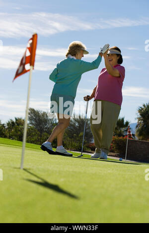 La femme High-Fiving sur Putting Green Banque D'Images