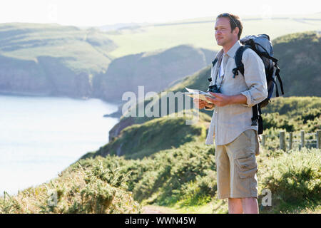 Homme debout sur le chemin perché holding map Banque D'Images