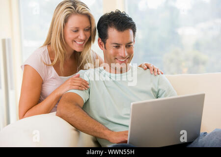 Couple dans la salle de séjour using laptop smiling Banque D'Images