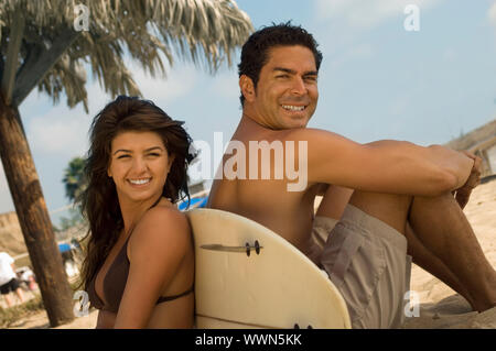 Surfer Cute Couple Sitting on Beach Banque D'Images