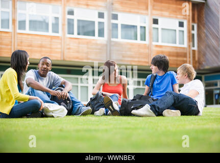 College students sitting et de parler sur le campus lawn Banque D'Images