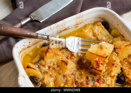 Le poisson avec des pommes de terre et les olives cuites au four dans la petite casserole Banque D'Images