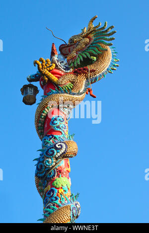 Golden dragon statue sur pilier rouge contre le ciel bleu Banque D'Images