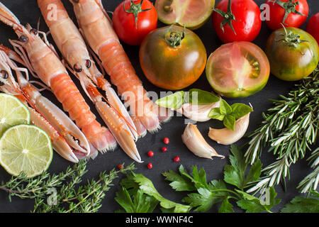 Langoustines crues avec légumes et fines herbes sur le fond sombre Banque D'Images