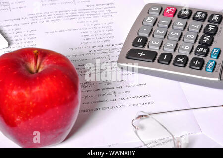 Exercices de mathématiques avec une calculatrice, verres et une pomme rouge à proximité. Banque D'Images