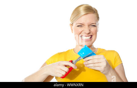 Femme grincement des dents tout en réduisant sa carte de crédit isolated over white Banque D'Images