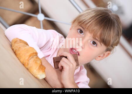 Jeune fille avec un croissant et barre de chocolat Banque D'Images