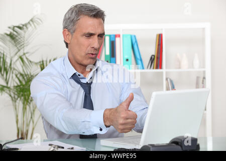 Middle-aged office worker giving thumbs-up Banque D'Images