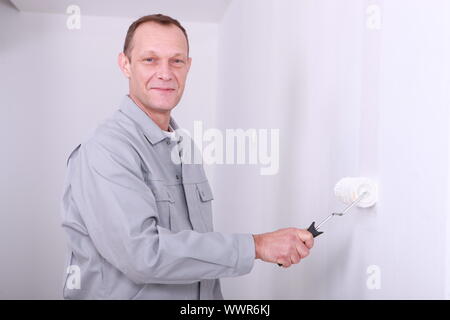 L'homme en salopette à peindre une chambre blanche Banque D'Images