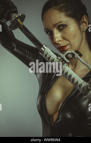 Brunette woman wearing latex noir, japonais katana Banque D'Images