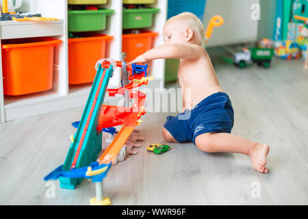 Cute baby boy playing with toy cars sur la bonne voie dans la chambre d'enfant Banque D'Images