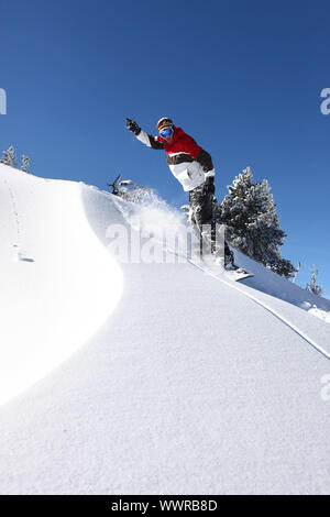 Snowboarder glisser en bas d'une pente Banque D'Images