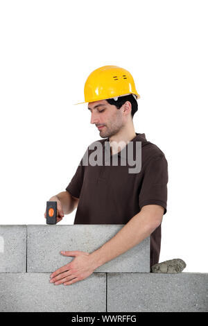 Mason en utilisant un marteau pour régler brick wall Banque D'Images