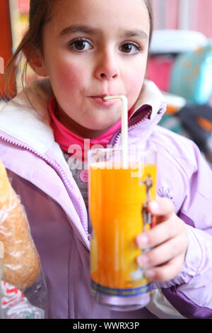 Petite fille boire du jus avec une paille Banque D'Images