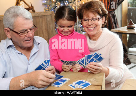 Petite fille jouant aux cartes avec ses grands-parents Banque D'Images