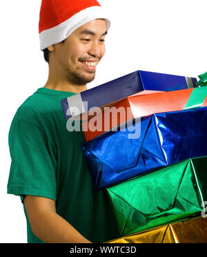 Un homme portant un chapeau de Père Noël et de transporter beaucoup de présente Banque D'Images