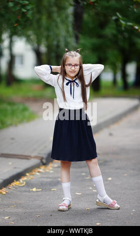 Lycéenne dans un uniforme scolaire posant. La jeune fille se tient à l'extérieur. Tir vertical. Focus sélectif. Banque D'Images