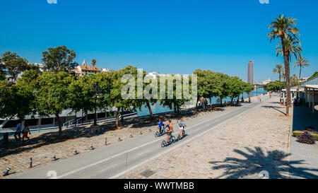 Séville, Espagne - Sept 9, 2019 : aux personnes bénéficiant d'activités de loisirs par Guadalquivir sur une belle après-midi d'été avec le pont Isabel II et Banque D'Images