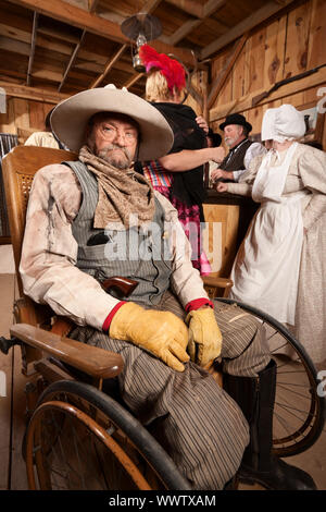 Mature blessés cowboy dans fauteuil roulant à old west saloon Banque D'Images