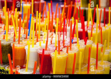 Jus de fruits frais naturels colorés verres avec paille empilés en rangées Banque D'Images