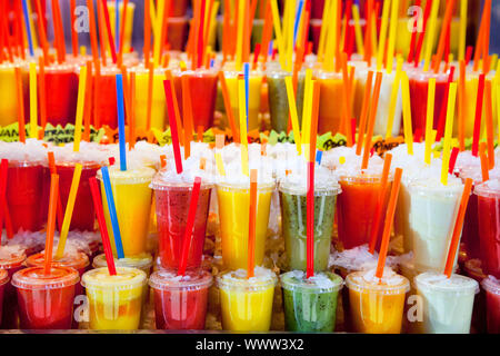 Jus de fruits frais naturels colorés verres avec paille empilés en rangées Banque D'Images