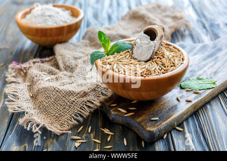 L'avoine à grains entiers et écope de la farine dans un bol en bois. Banque D'Images