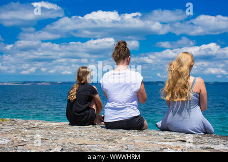 Trois filles photographiés par derrière pendant qu'ils sont à la recherche de l'océan à Camaret-sur-Mer en France Banque D'Images