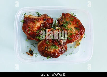 Cuisses de poulet frit avec des greens dans un récipient de stockage sur un fond bleu. Ruddy croûte. Banque D'Images