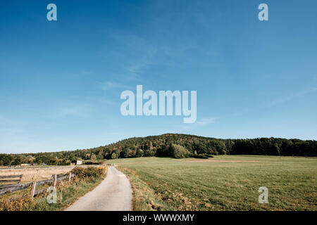 La fin de l'été magnifique paysage dans la campagne avec une route de gravier, de prairies, d'une clôture et la colline appelée Moritzberg près de Haimendorf, Allemagne Banque D'Images