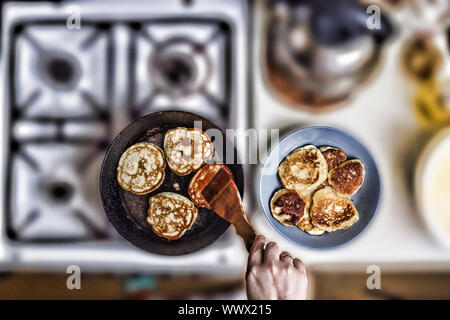 Femme fry crêpes dans une poêle sur une vieille cuisinière à gaz. Concept : la cuisson. Vue de dessus. F Banque D'Images