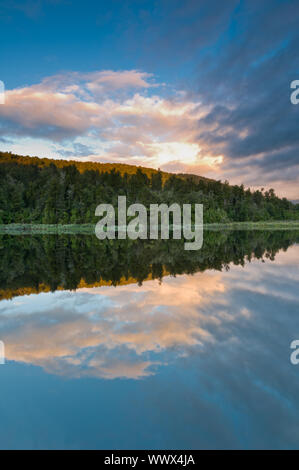 Lever du soleil au-dessus d'un lac sur un matin encore du vent et le ciel se reflète dans le lac Banque D'Images