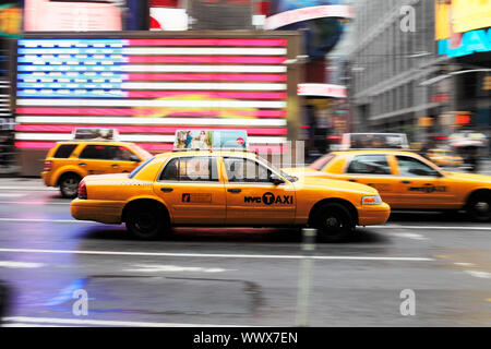 La VILLE DE NEW YORK, USA - 12 juin : Yellow taxi cab sur Times Square. Un drapeau américain en arrière-plan. 12 juin 2012 à New York City, USA Banque D'Images