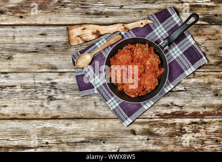 Les boulettes à la sauce tomate dans une poêle sur une table en bois, vue du dessus, style rural Banque D'Images