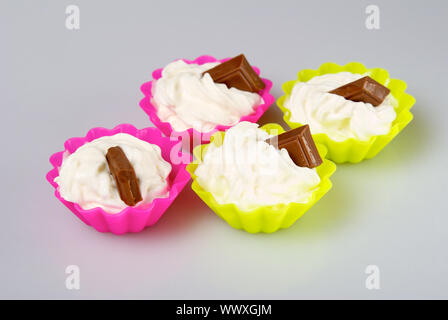 Quatre portions de crème fouettée sur fond blanc. Banque D'Images