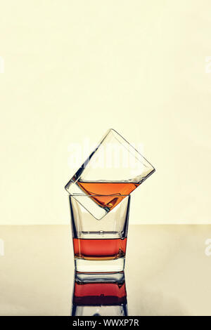 De whisky, de rhum ou de cognac dans deux verres sur la table avec la réflexion. Concept : l'alcool de luxe. Banque D'Images