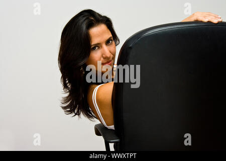 Une belle jeune femme latina assis dans une chaise de bureau et à l'arrière, isolated on white Banque D'Images