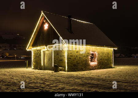 Petite maison avec fairy lights dans la nuit et la neige, de Malters, Lucerne, Suisse, les saisons Banque D'Images