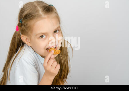 Portrait d'une petite fillette de six ans de mordre un cookie Banque D'Images