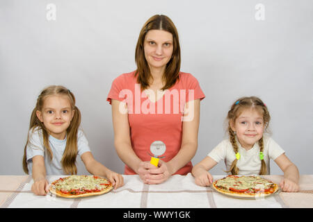 À la table de sam ma mère avec un couteau à pizza et deux filles à qui deux pizzas Banque D'Images