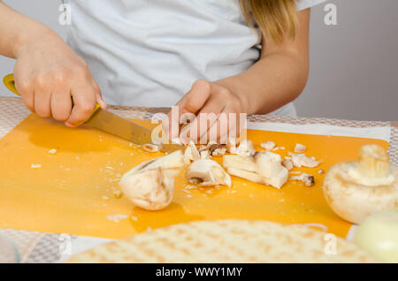 Close-up de mains d'enfants, les champignons couteau de coupe sur une planche à découper Banque D'Images