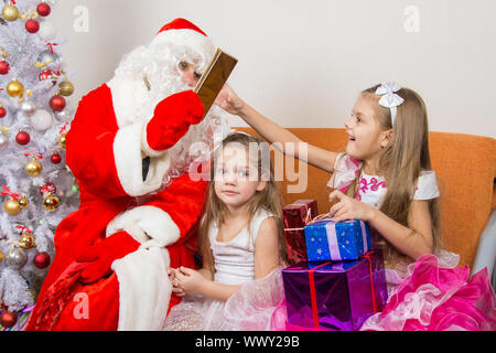 Le Père Noël donne des cadeaux pour une fille, l'autre était assis dans la salle d'attente Banque D'Images