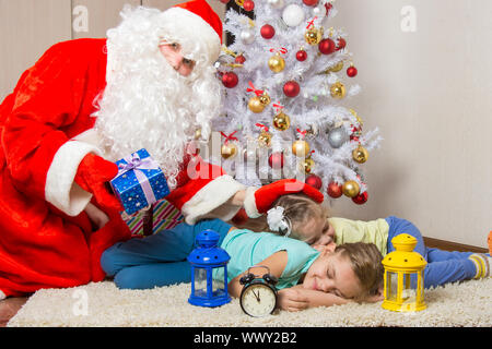 Le Père Noël a apporté des cadeaux, tape sur la tête de coucher l'enfant, et le regarda dans le cadre Banque D'Images