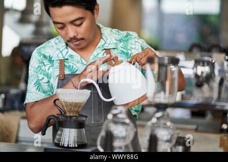 Vie candide shot of indonesian ethniques barista et propriétaire de petite entreprise la préparation du café bio-équitable dans un café branché Banque D'Images