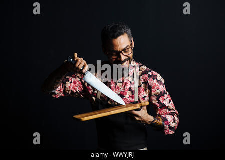 Portrait d'un homme avec une planche à découper et couteau de boucher, isolés dans un contexte de studio Banque D'Images